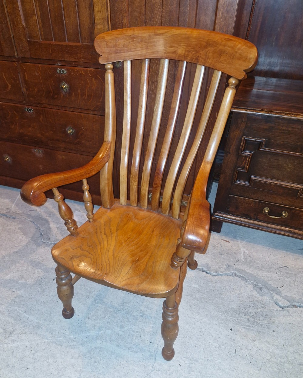 A Victorian wooden Windsor armchair featuring a shaped crest rail, vertical spindles, a contoured saddle seat, curved armrests, and turned legs. View V