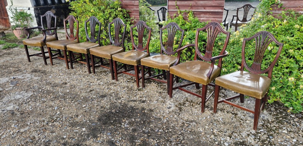 A set of eight mahogany dining chairs with carved shield backrests and leather seats positioned in a line. View VIII