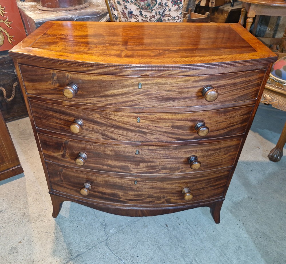 An early 19th-century mahogany bow front chest of drawers featuring four graduated drawers with turned wooden knobs and splayed feet. View II