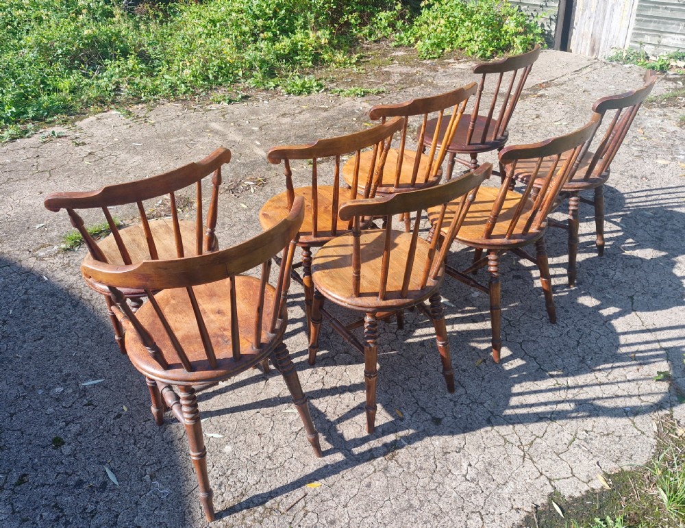 A set of eight matched antique wooden kitchen chairs featuring circular seats, spindle backs, curved crest rails, and turned legs. View II