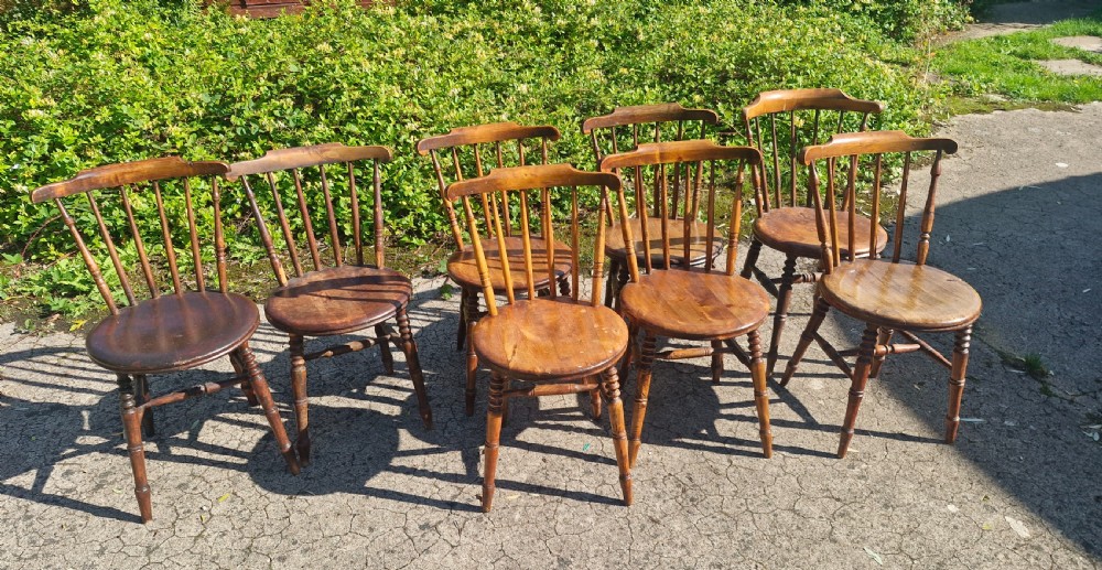 A set of eight matched antique wooden kitchen chairs featuring circular seats, spindle backs, curved crest rails, and turned legs. View IV