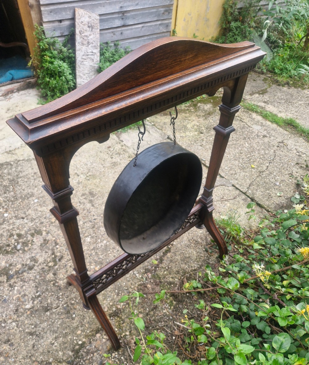 A Victorian carved oak floor-standing frame featuring a shell-carved pediment and open fretwork base, holding a suspended circular metal gong. View III