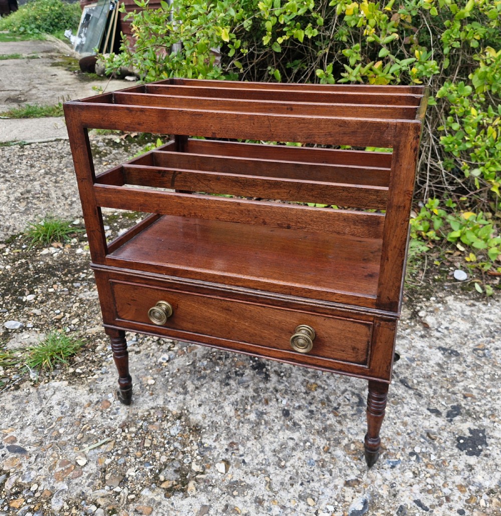 A Regency mahogany music Canterbury featuring slotted upper dividers, a single lower drawer with brass knobs, and turned legs with brass castors.