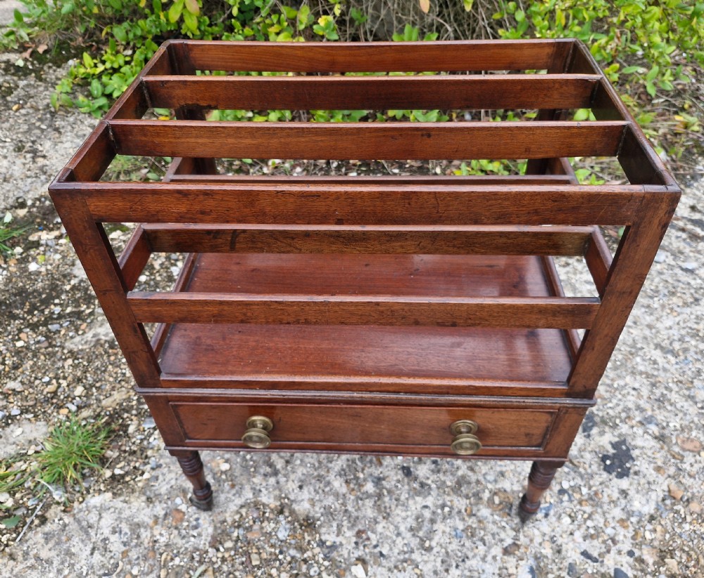 A Regency mahogany music Canterbury featuring slotted upper dividers, a single lower drawer with brass knobs, and turned legs with brass castors. View II