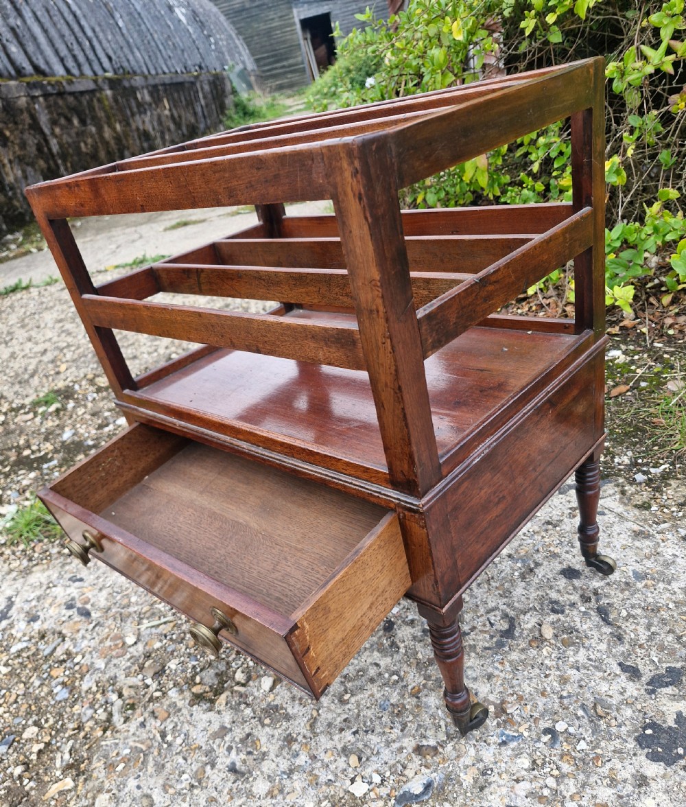 A Regency mahogany music Canterbury featuring slotted upper dividers, a single lower drawer with brass knobs, and turned legs with brass castors. View V