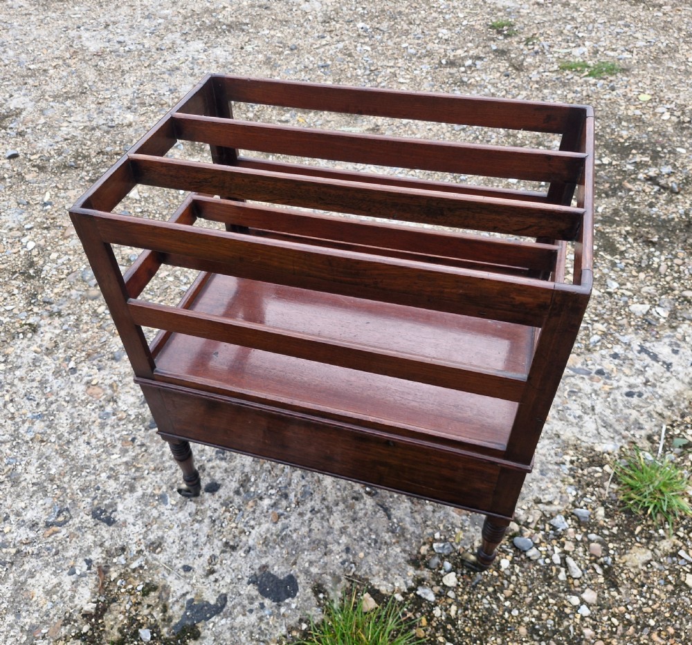 A Regency mahogany music Canterbury featuring slotted upper dividers, a single lower drawer with brass knobs, and turned legs with brass castors. View VI