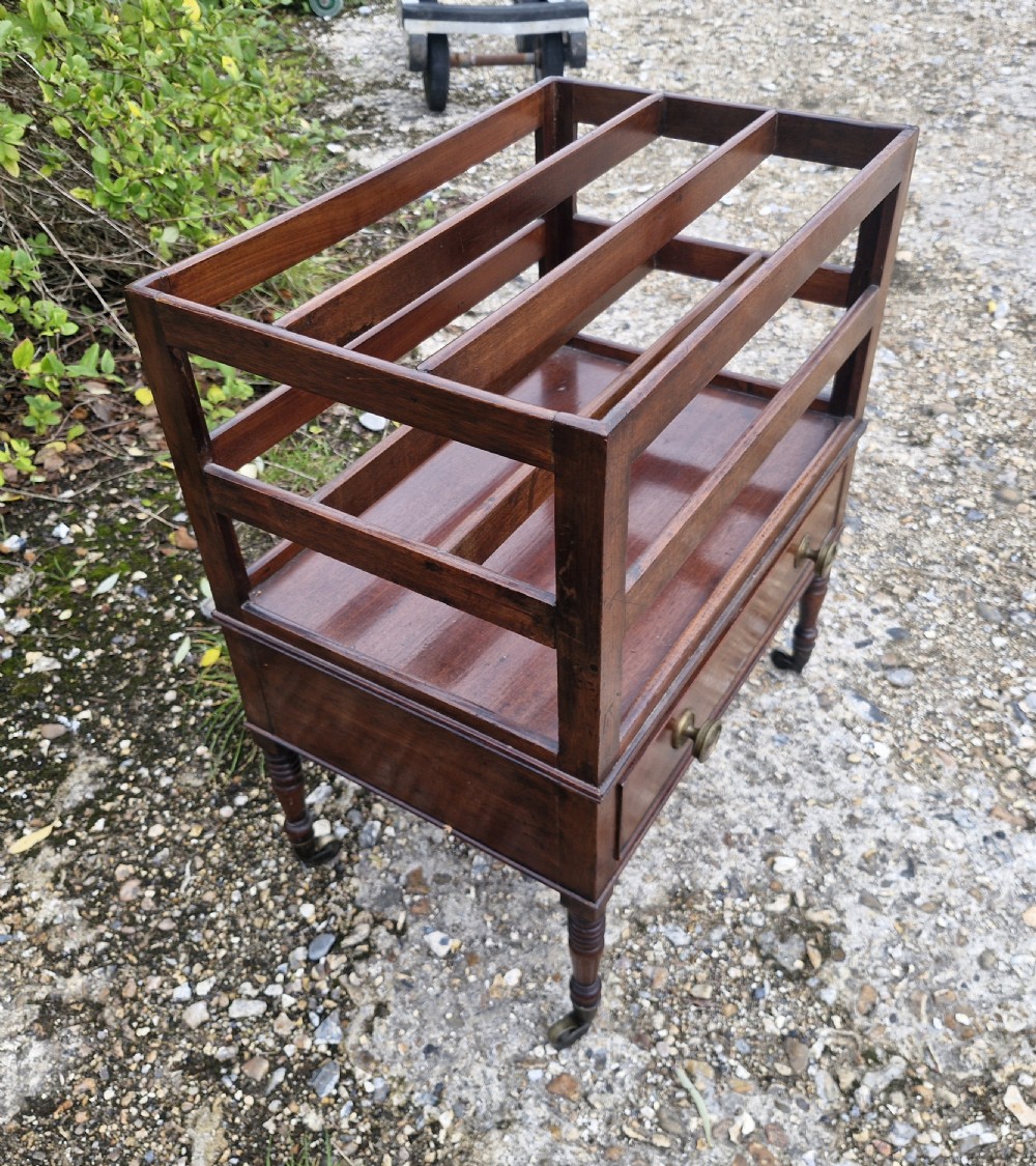 A Regency mahogany music Canterbury featuring slotted upper dividers, a single lower drawer with brass knobs, and turned legs with brass castors. View VII