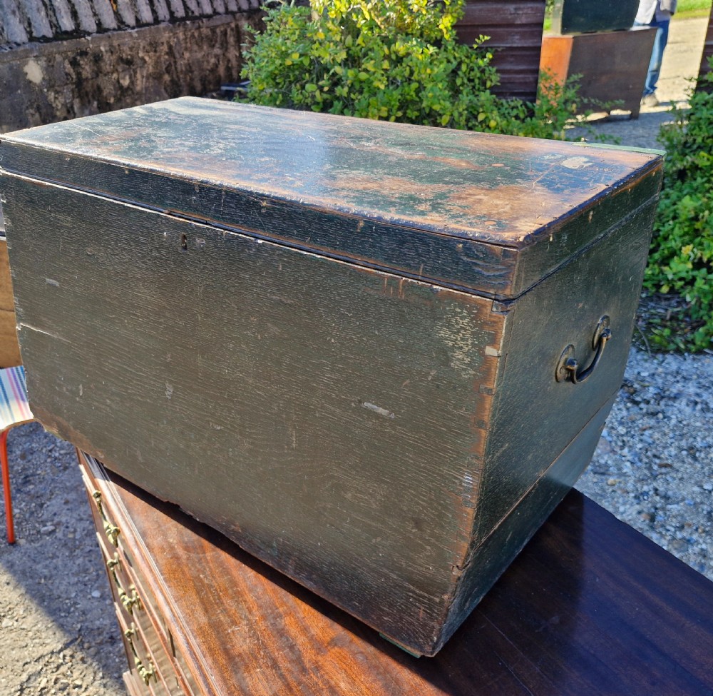 An early 19th-century rectangular oak coaching trunk featuring a distressed dark green painted finish, brass side handles, hand-cut dovetail joints, and an iron keyhole escutcheon. View III