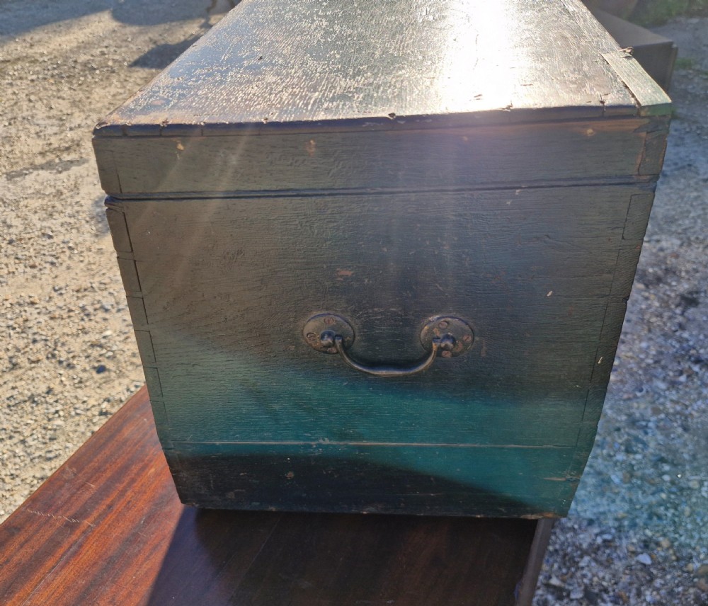 An early 19th-century rectangular oak coaching trunk featuring a distressed dark green painted finish, brass side handles, hand-cut dovetail joints, and an iron keyhole escutcheon. View V