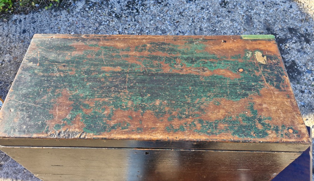 An early 19th-century rectangular oak coaching trunk featuring a distressed dark green painted finish, brass side handles, hand-cut dovetail joints, and an iron keyhole escutcheon. View X