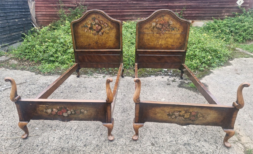 A pair of antique walnut single bed frames featuring arched headboards with floral painted leather panels and scrolled footboard posts. View II