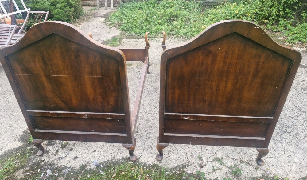 A pair of antique walnut single bed frames featuring arched headboards with floral painted leather panels and scrolled footboard posts. View V