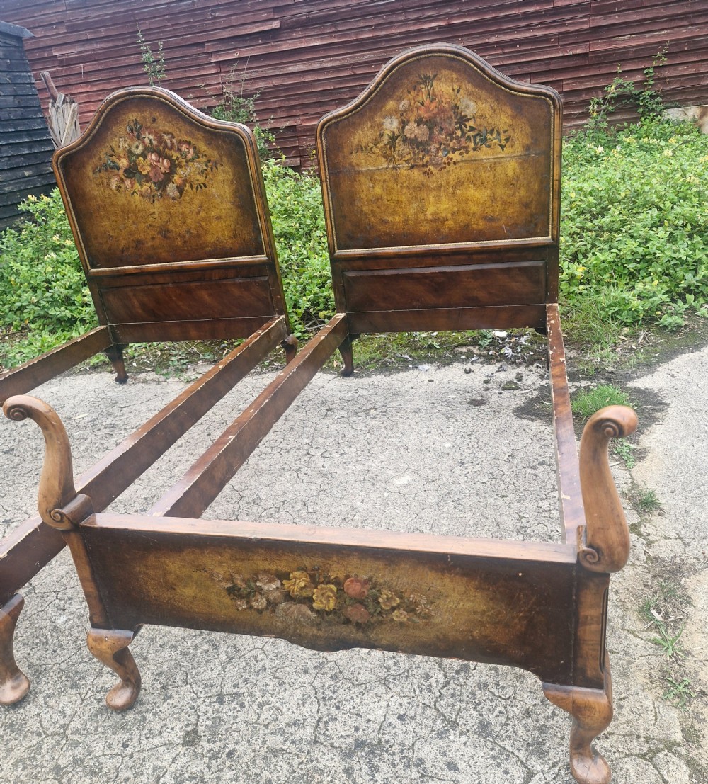 A pair of antique walnut single bed frames featuring arched headboards with floral painted leather panels and scrolled footboard posts. View VII