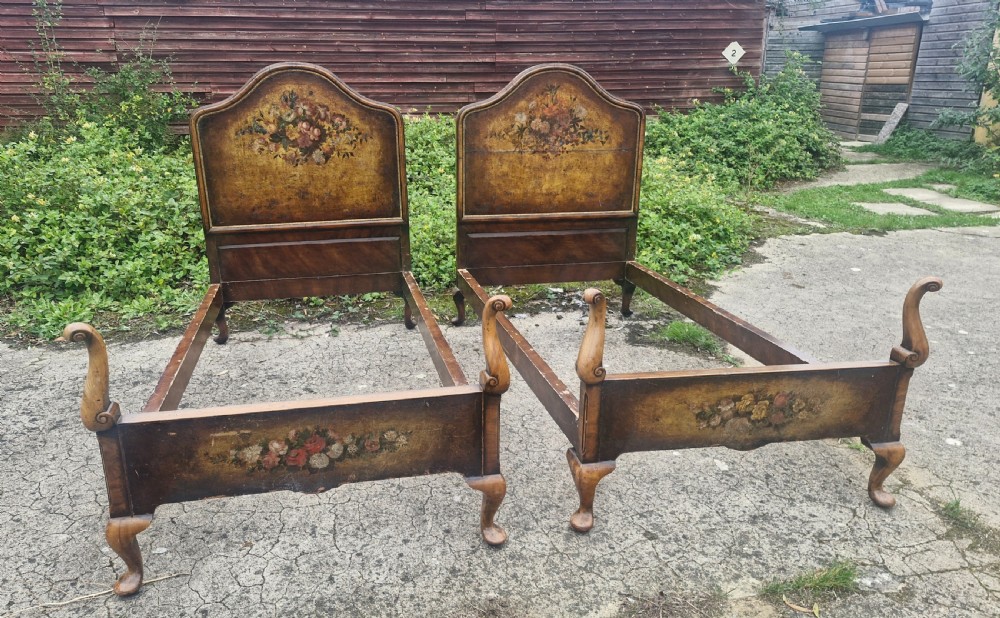 A pair of antique walnut single bed frames featuring arched headboards with floral painted leather panels and scrolled footboard posts. View IX