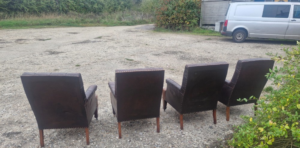Set of four dark brown leather armchairs featuring deep button tufting, brass studding, and square tapered legs with castors. View VII