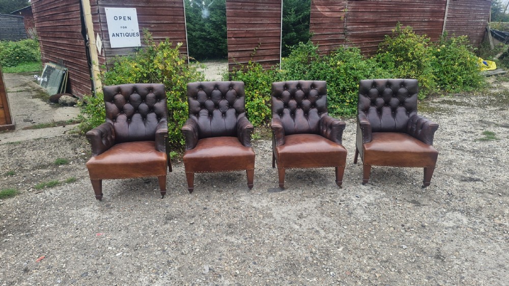 Set of four dark brown leather armchairs featuring deep button tufting, brass studding, and square tapered legs with castors. View VIII