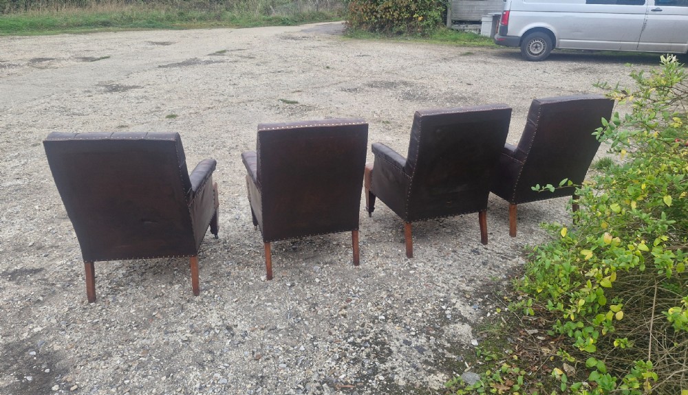 Set of four dark brown leather armchairs featuring deep button tufting, brass studding, and square tapered legs with castors. View IX