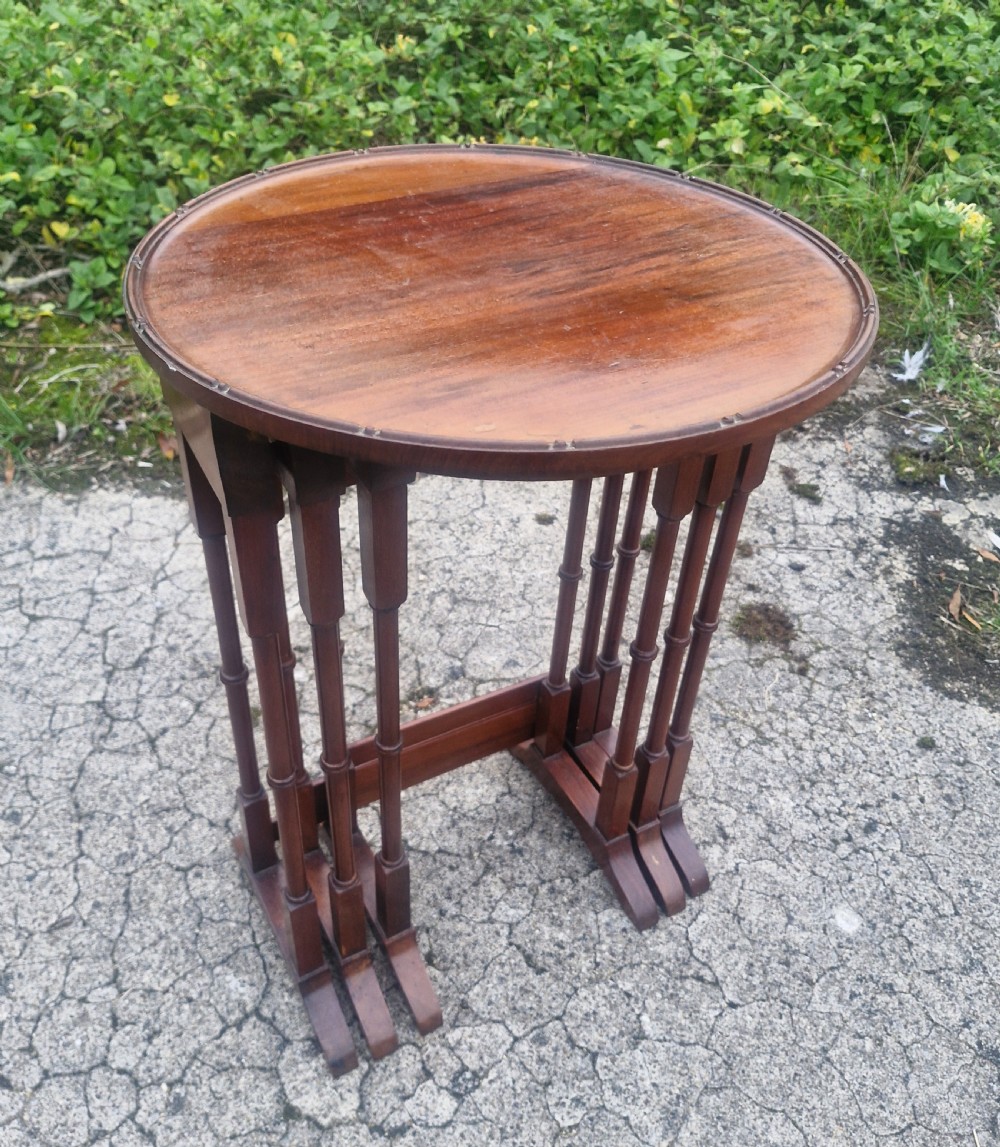A nest of three Edwardian mahogany occasional tables featuring oval tops with moulded borders and slender turned legs. View II