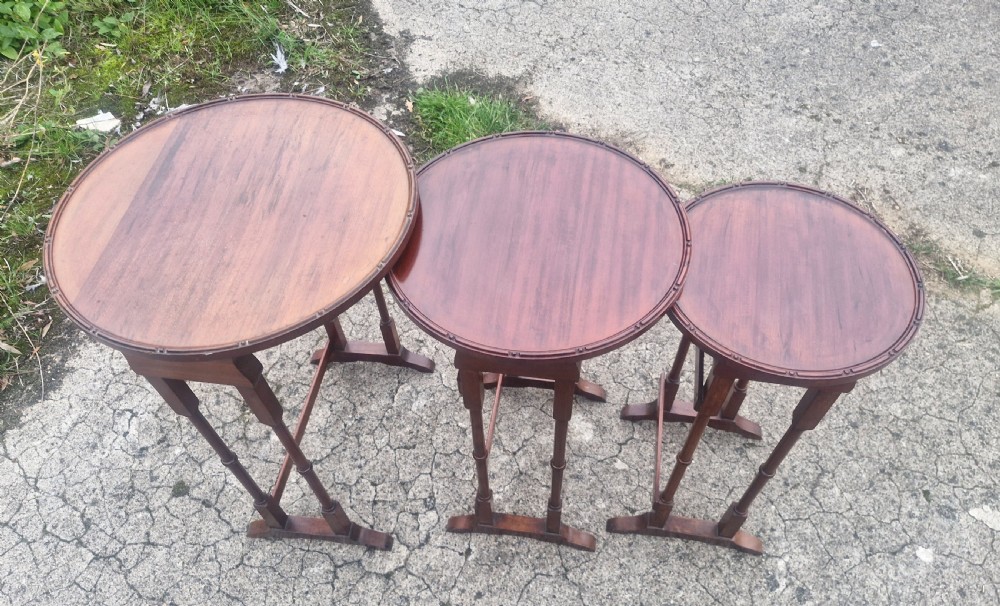 A nest of three Edwardian mahogany occasional tables featuring oval tops with moulded borders and slender turned legs. View III