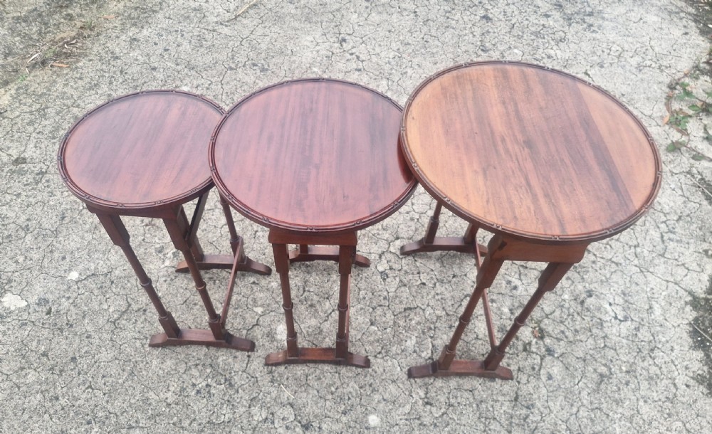 A nest of three Edwardian mahogany occasional tables featuring oval tops with moulded borders and slender turned legs. View V