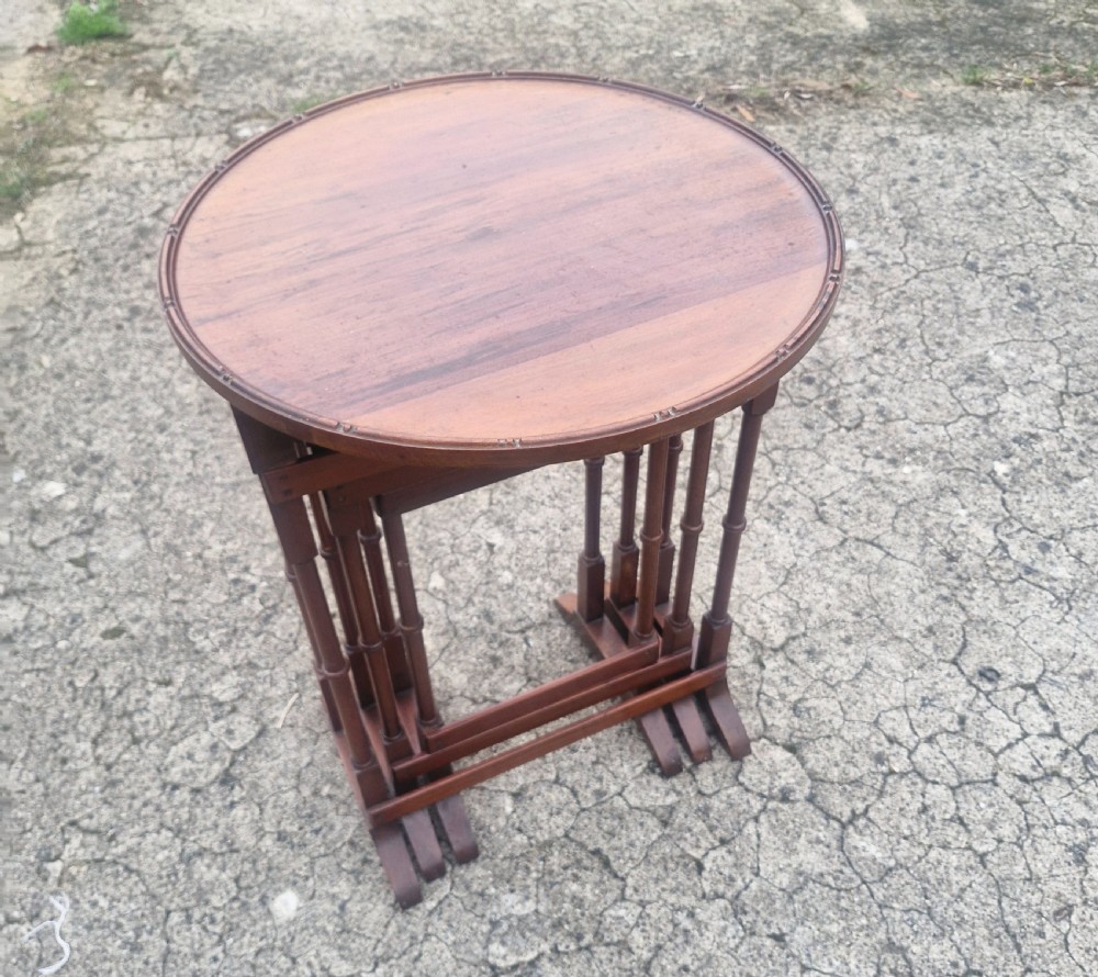 A nest of three Edwardian mahogany occasional tables featuring oval tops with moulded borders and slender turned legs. View VI