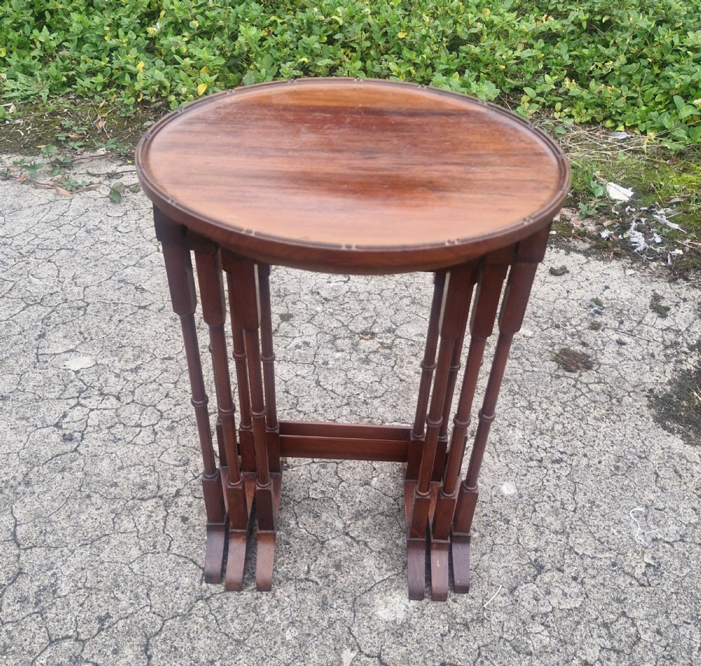 A nest of three Edwardian mahogany occasional tables featuring oval tops with moulded borders and slender turned legs. View VII