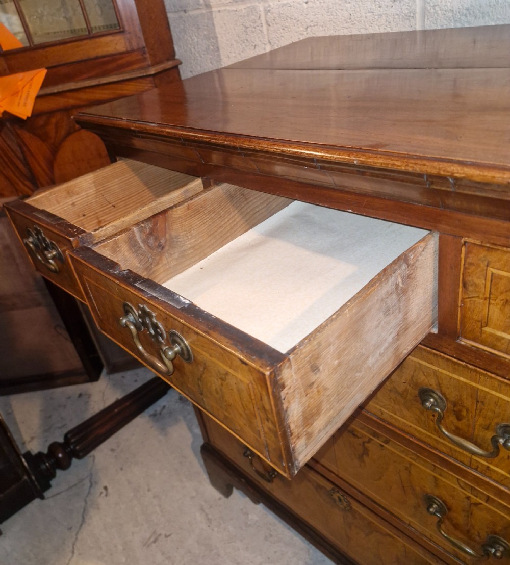 An 18th-century walnut chest of drawers featuring three small top drawers above three long drawers with brass drop handles and bracket feet. View II