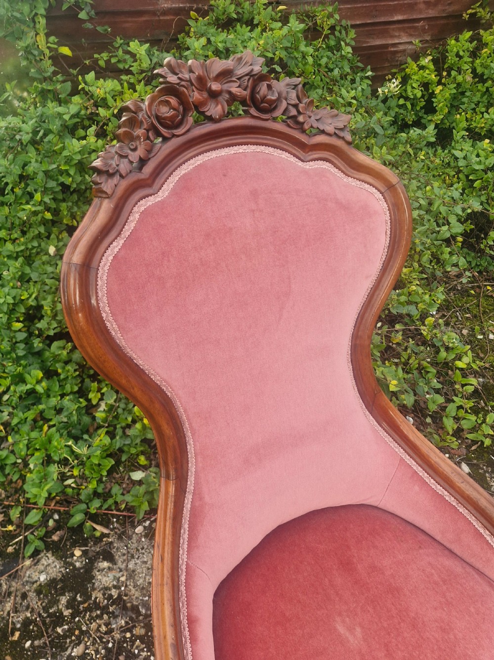 A late Victorian mahogany nursing chair upholstered in dusty rose pink velvet with hand-carved floral detailing on the top rail. View IV