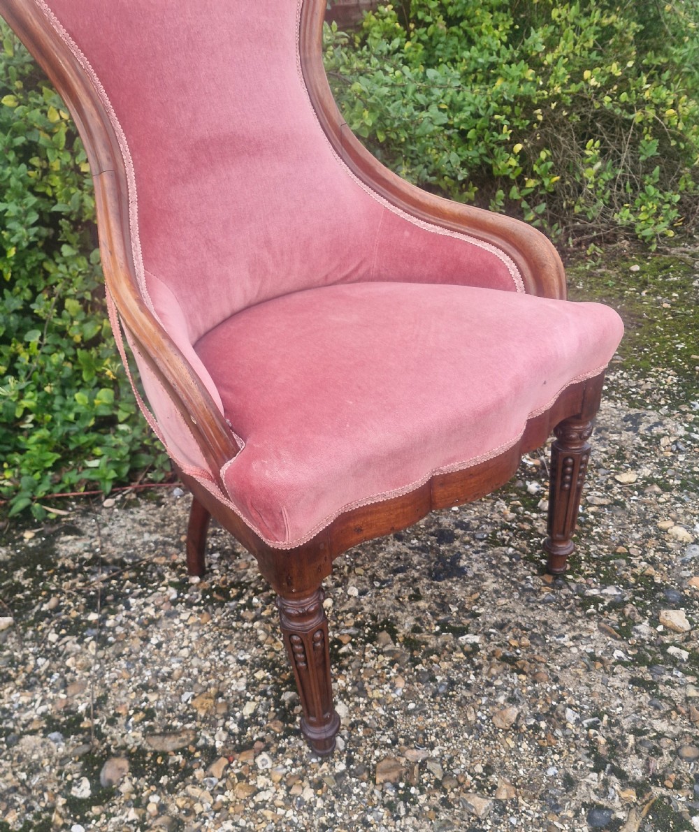 A late Victorian mahogany nursing chair upholstered in dusty rose pink velvet with hand-carved floral detailing on the top rail. View V
