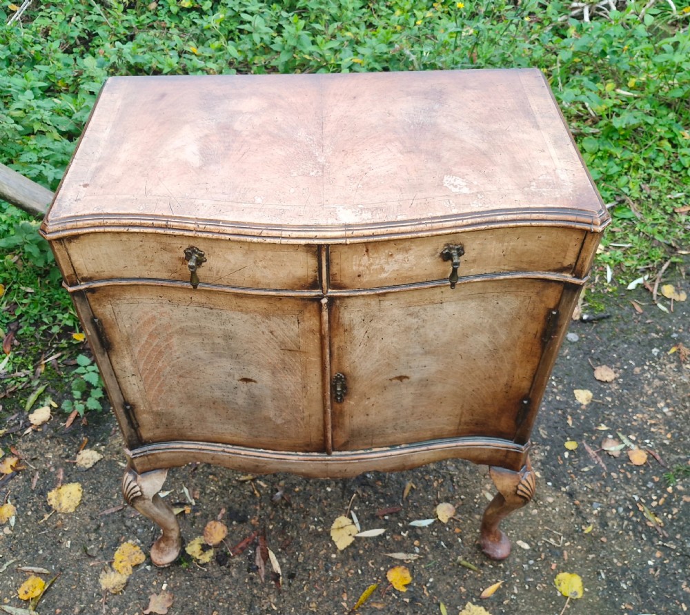 An early 20th-century walnut side cabinet featuring two doors, a serpentine front, drop brass handles, and cabriole legs with shell-carved knees. View II