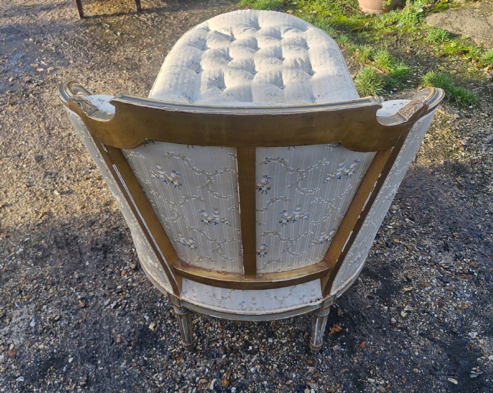 An early 20th-century French style giltwood day bed featuring button-tufted cream floral fabric, fluted tapered legs, and an asymmetrical curved backrest. View V