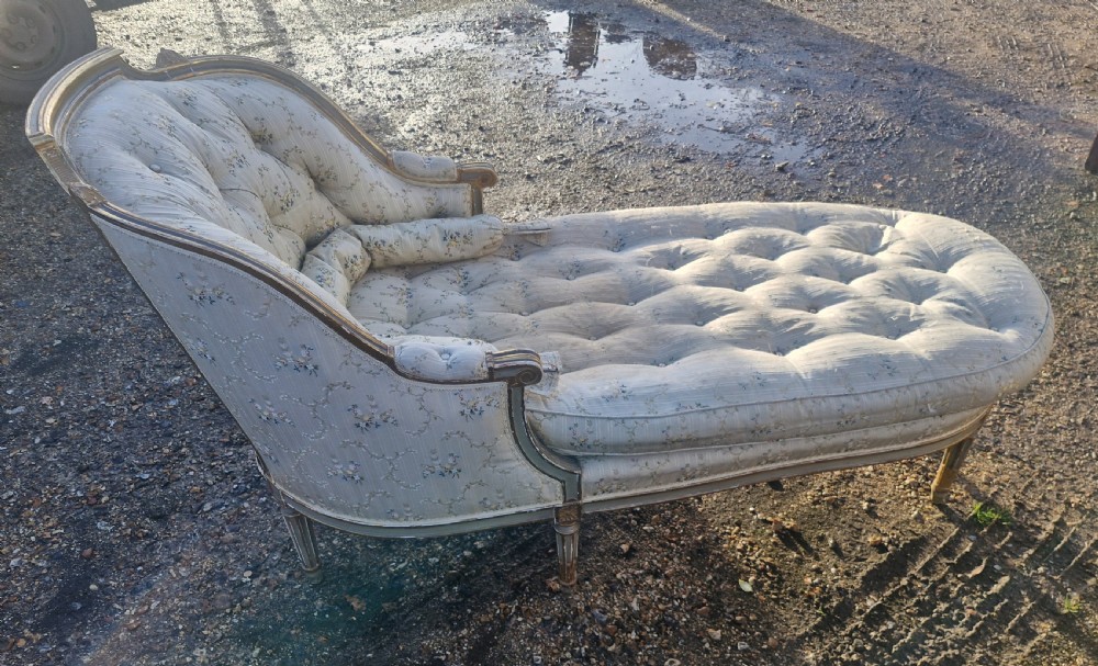 An early 20th-century French style giltwood day bed featuring button-tufted cream floral fabric, fluted tapered legs, and an asymmetrical curved backrest. View VI