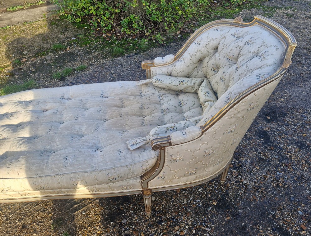 An early 20th-century French style giltwood day bed featuring button-tufted cream floral fabric, fluted tapered legs, and an asymmetrical curved backrest. View VII