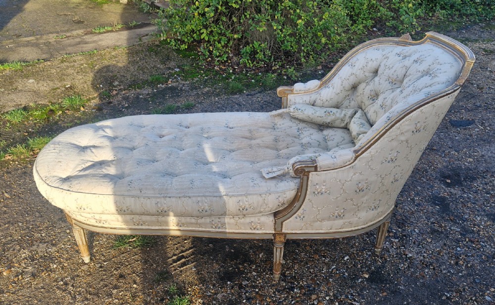 An early 20th-century French style giltwood day bed featuring button-tufted cream floral fabric, fluted tapered legs, and an asymmetrical curved backrest. View X