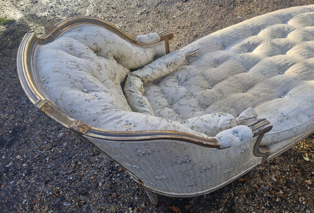 An early 20th-century French style giltwood day bed featuring button-tufted cream floral fabric, fluted tapered legs, and an asymmetrical curved backrest. View XII