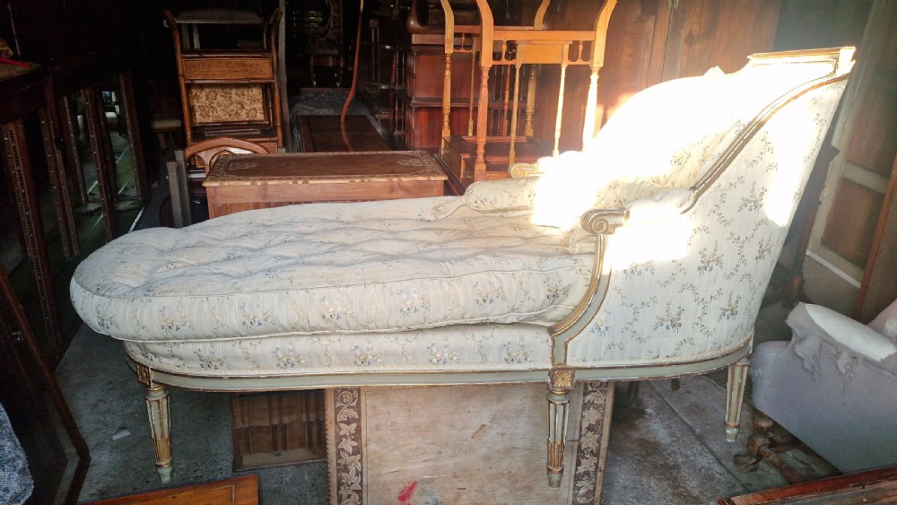 An early 20th-century French style giltwood day bed featuring button-tufted cream floral fabric, fluted tapered legs, and an asymmetrical curved backrest. View XVI