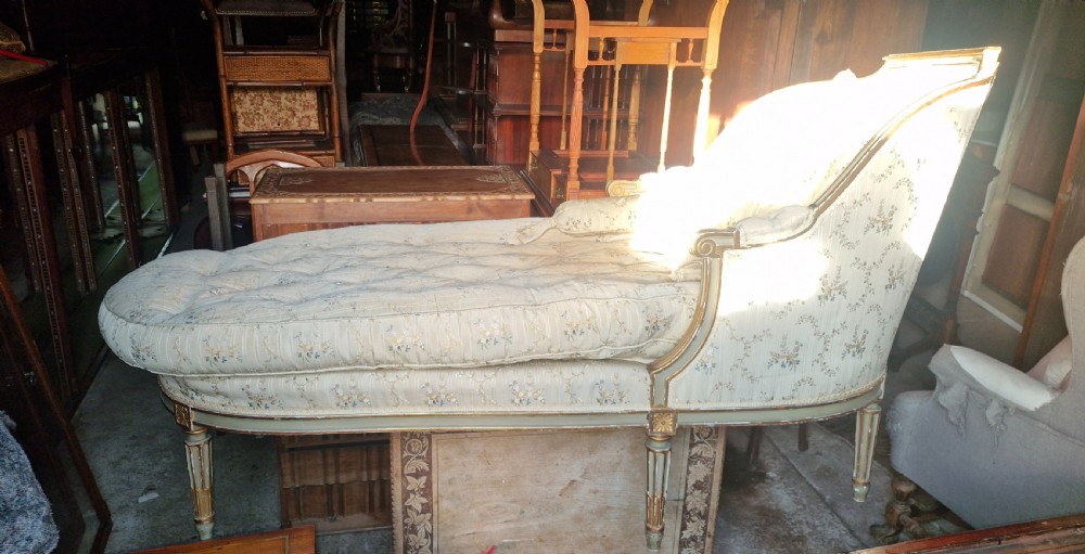An early 20th-century French style giltwood day bed featuring button-tufted cream floral fabric, fluted tapered legs, and an asymmetrical curved backrest. View XVII