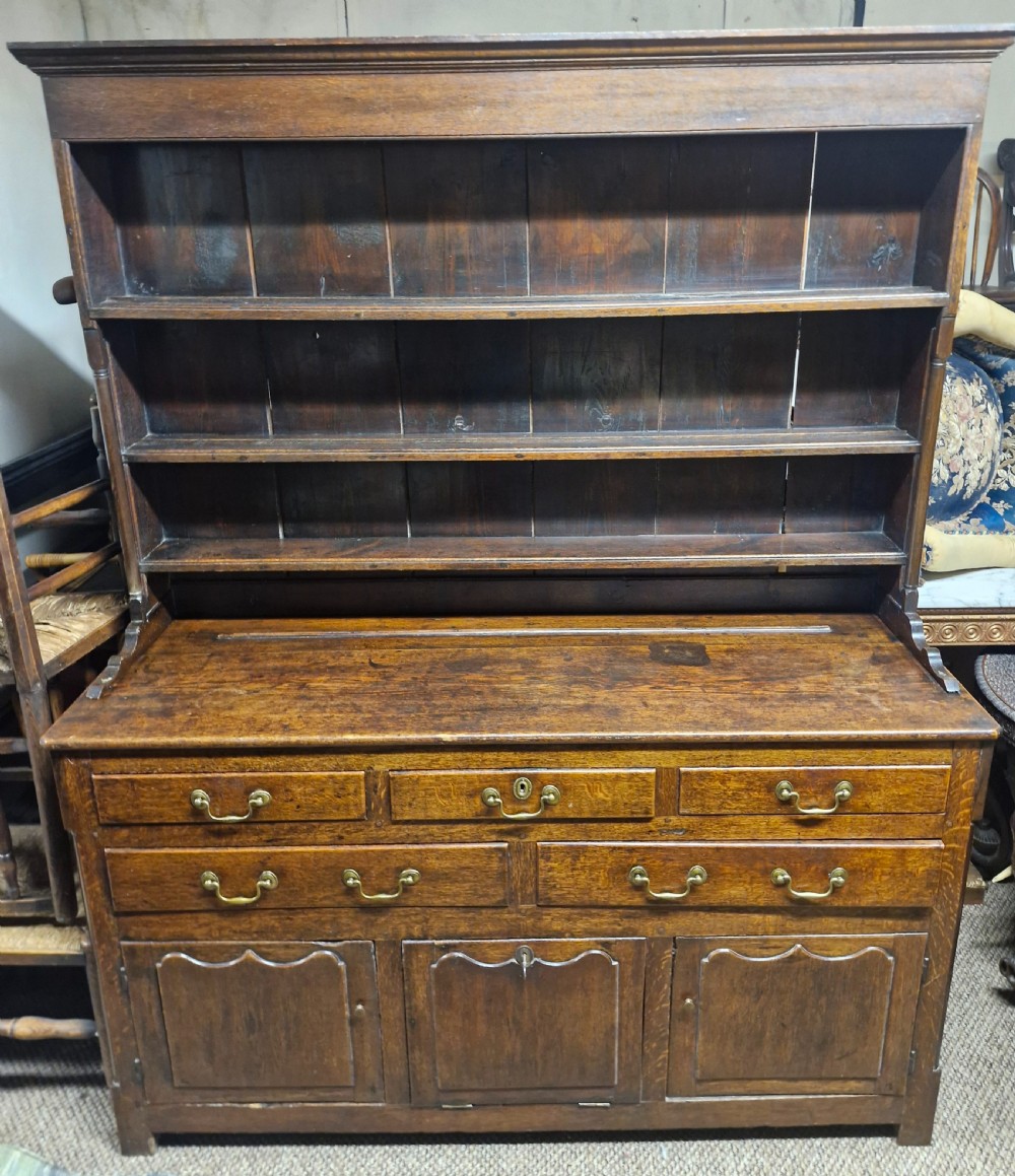 An early nineteenth-century two-part dark oak Welsh dresser featuring a three-shelf plate rack over a sideboard base with drawers and fielded panel cupboard doors. View II