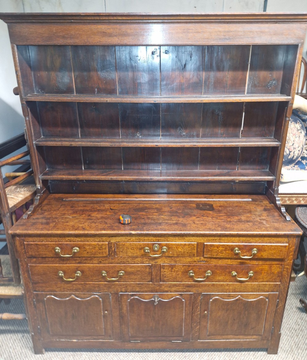 An early nineteenth-century two-part dark oak Welsh dresser featuring a three-shelf plate rack over a sideboard base with drawers and fielded panel cupboard doors. View III
