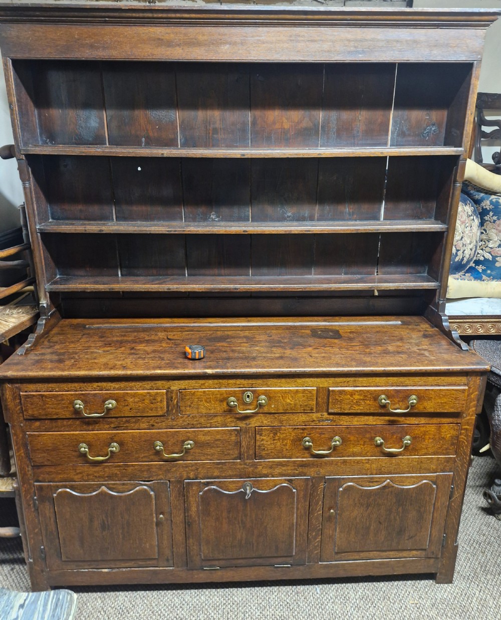 An early nineteenth-century two-part dark oak Welsh dresser featuring a three-shelf plate rack over a sideboard base with drawers and fielded panel cupboard doors. View V