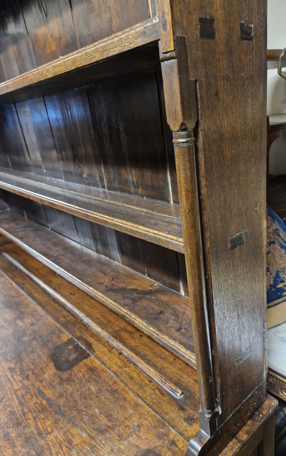 An early nineteenth-century two-part dark oak Welsh dresser featuring a three-shelf plate rack over a sideboard base with drawers and fielded panel cupboard doors. View VI