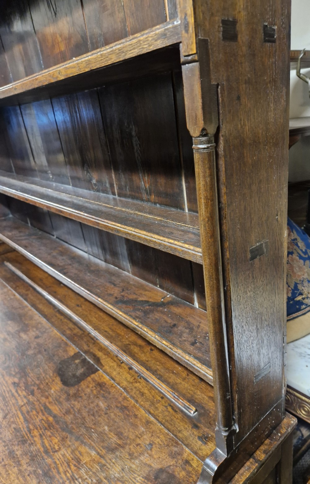 An early nineteenth-century two-part dark oak Welsh dresser featuring a three-shelf plate rack over a sideboard base with drawers and fielded panel cupboard doors. View VII