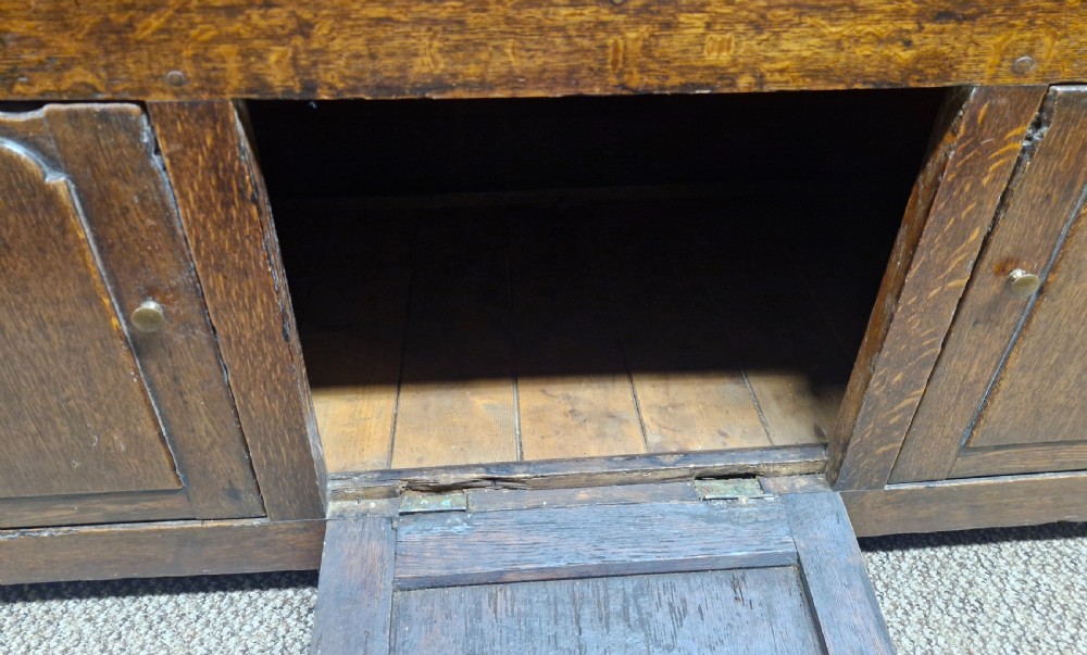 An early nineteenth-century two-part dark oak Welsh dresser featuring a three-shelf plate rack over a sideboard base with drawers and fielded panel cupboard doors. View VIII