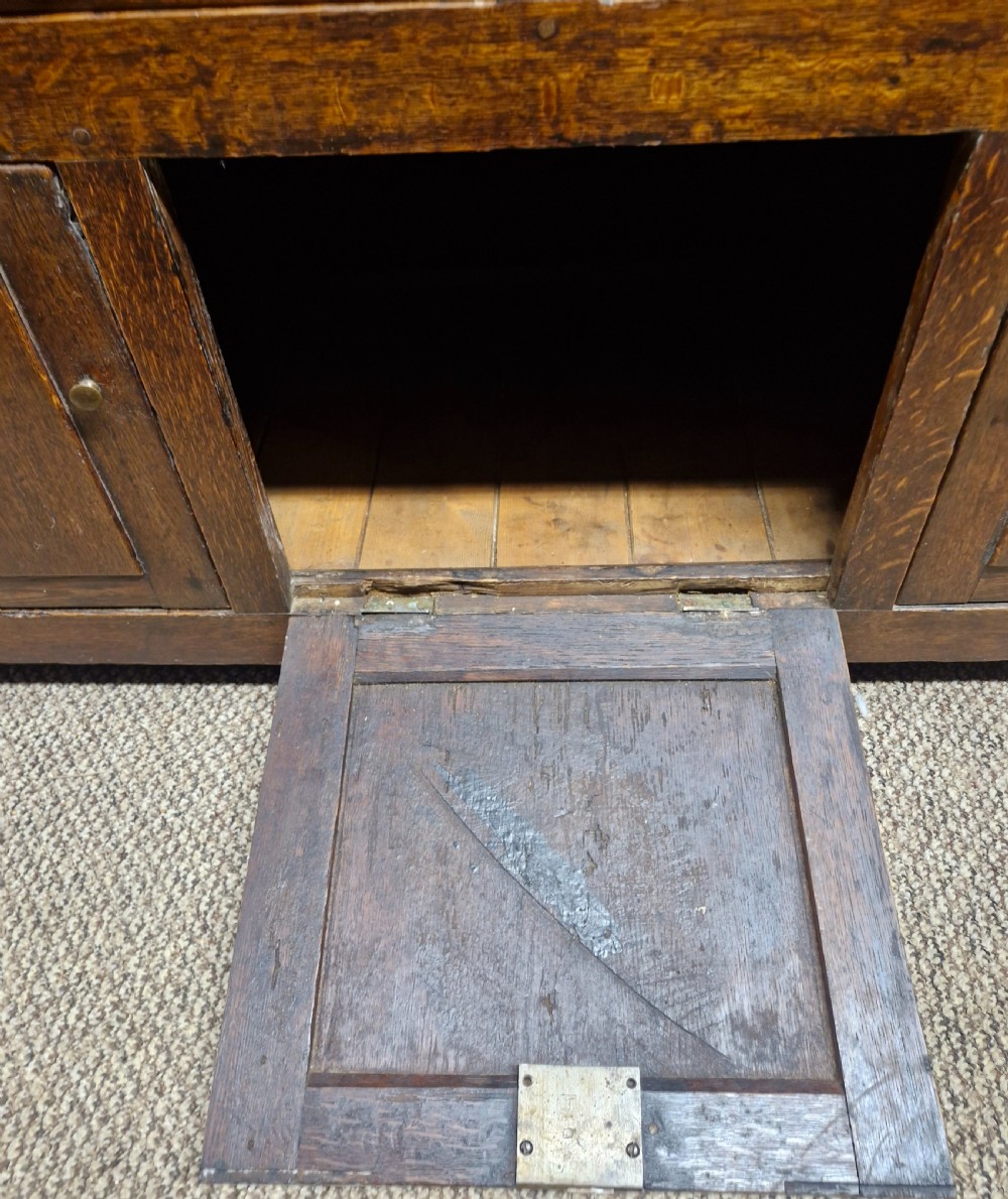 An early nineteenth-century two-part dark oak Welsh dresser featuring a three-shelf plate rack over a sideboard base with drawers and fielded panel cupboard doors. View IX