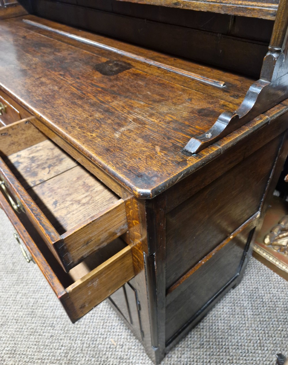 An early nineteenth-century two-part dark oak Welsh dresser featuring a three-shelf plate rack over a sideboard base with drawers and fielded panel cupboard doors. View XVI