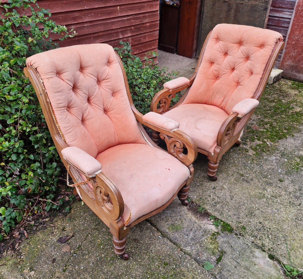 A pair of Victorian mahogany library armchairs featuring button-tufted peach fabric upholstery, scrolled wooden armrests, and turned front legs on casters. View III