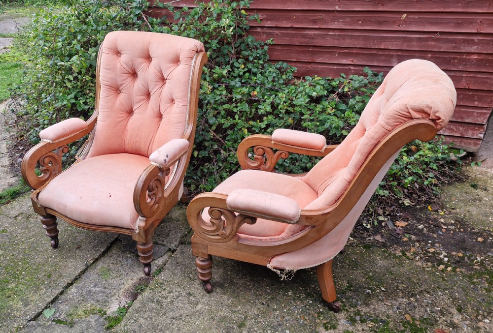 A pair of Victorian mahogany library armchairs featuring button-tufted peach fabric upholstery, scrolled wooden armrests, and turned front legs on casters. View VII