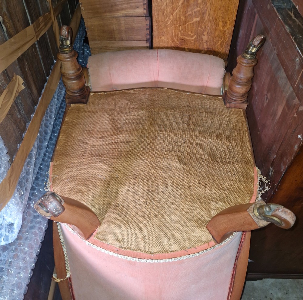 A pair of Victorian mahogany library armchairs featuring button-tufted peach fabric upholstery, scrolled wooden armrests, and turned front legs on casters. View IX