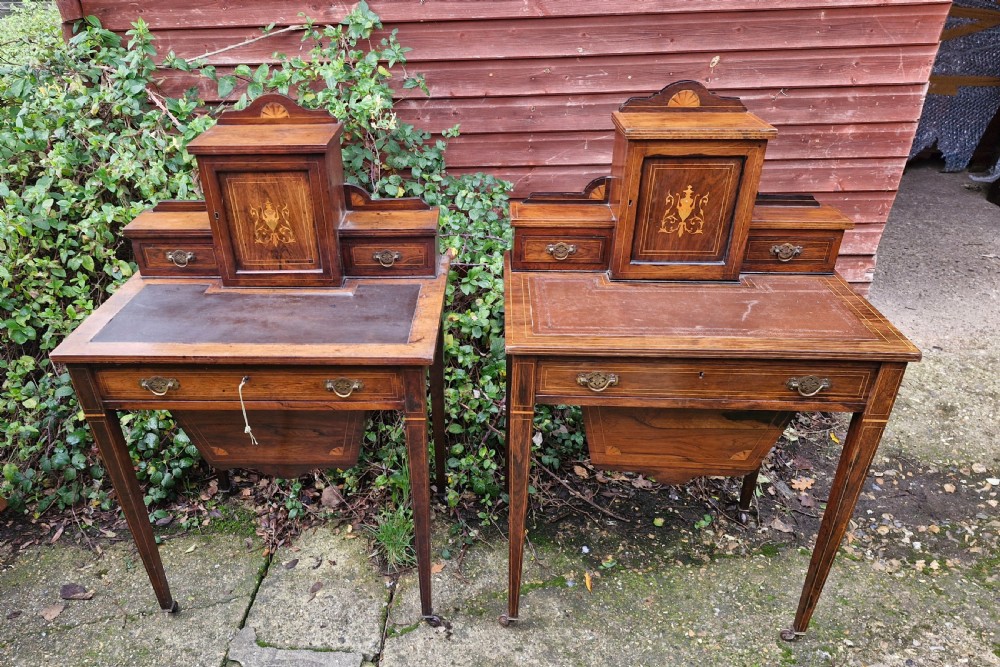 A pair of late Victorian rosewood writing tables featuring central raised cupboards with urn inlay, leather surfaces, and tapered square legs.
