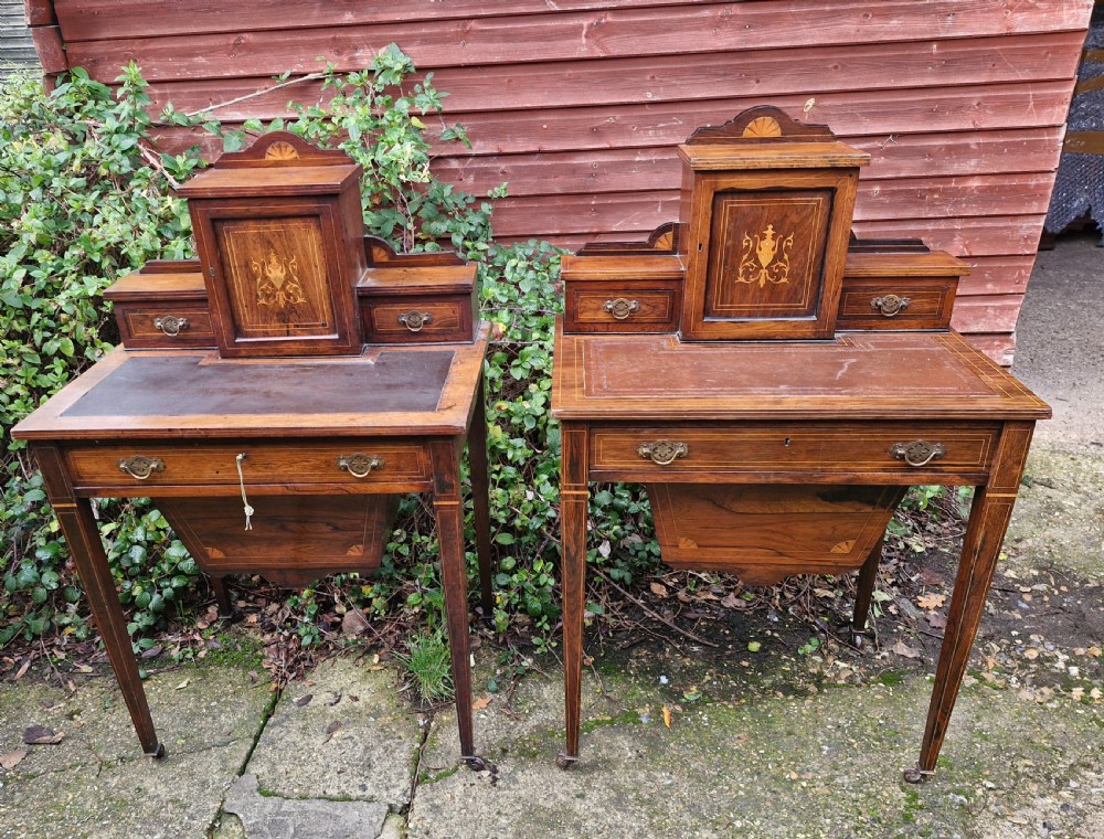 A pair of late Victorian rosewood writing tables featuring central raised cupboards with urn inlay, leather surfaces, and tapered square legs. View V